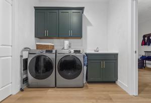 Modern laundry room wwith green cabinets and stainless steel washer and dryer, Located in Columbia, IL.