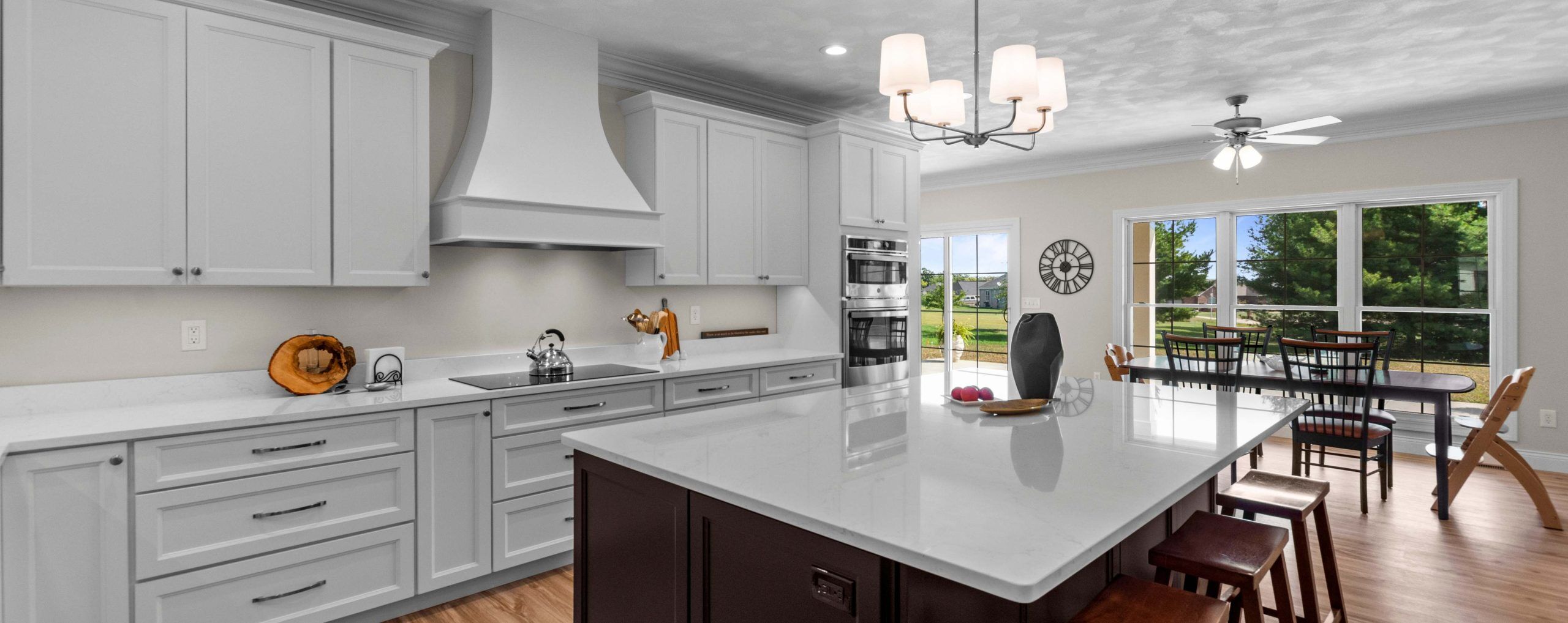 Beautiful modern bright kitchen. The island has dark wood cabinets while the perimeter cabinets a white wood with white quartz counters.