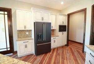Modern kitchen with white cabinets and a black refrigerator.&nbsp;