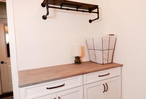 Rustic laundry room with natural wood counter tops and Ivory Koch Cabinets and iron shelf.