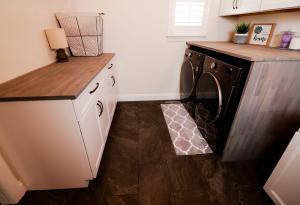 Rustic laundry room with natural wood counter tops and Ivory Koch Cabinets.