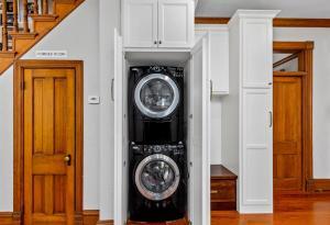 A stand up washer and dryer, tucked away in custom white cabinet.