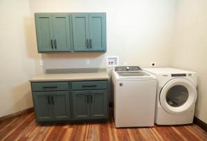 Laundry room upgraded with custom Koch Cabinets in green with white appliances.