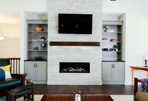 Modern Living room with a white stone built fireplace and custom built-in cabinets, designed by Studio 11 Cabinets and Design.